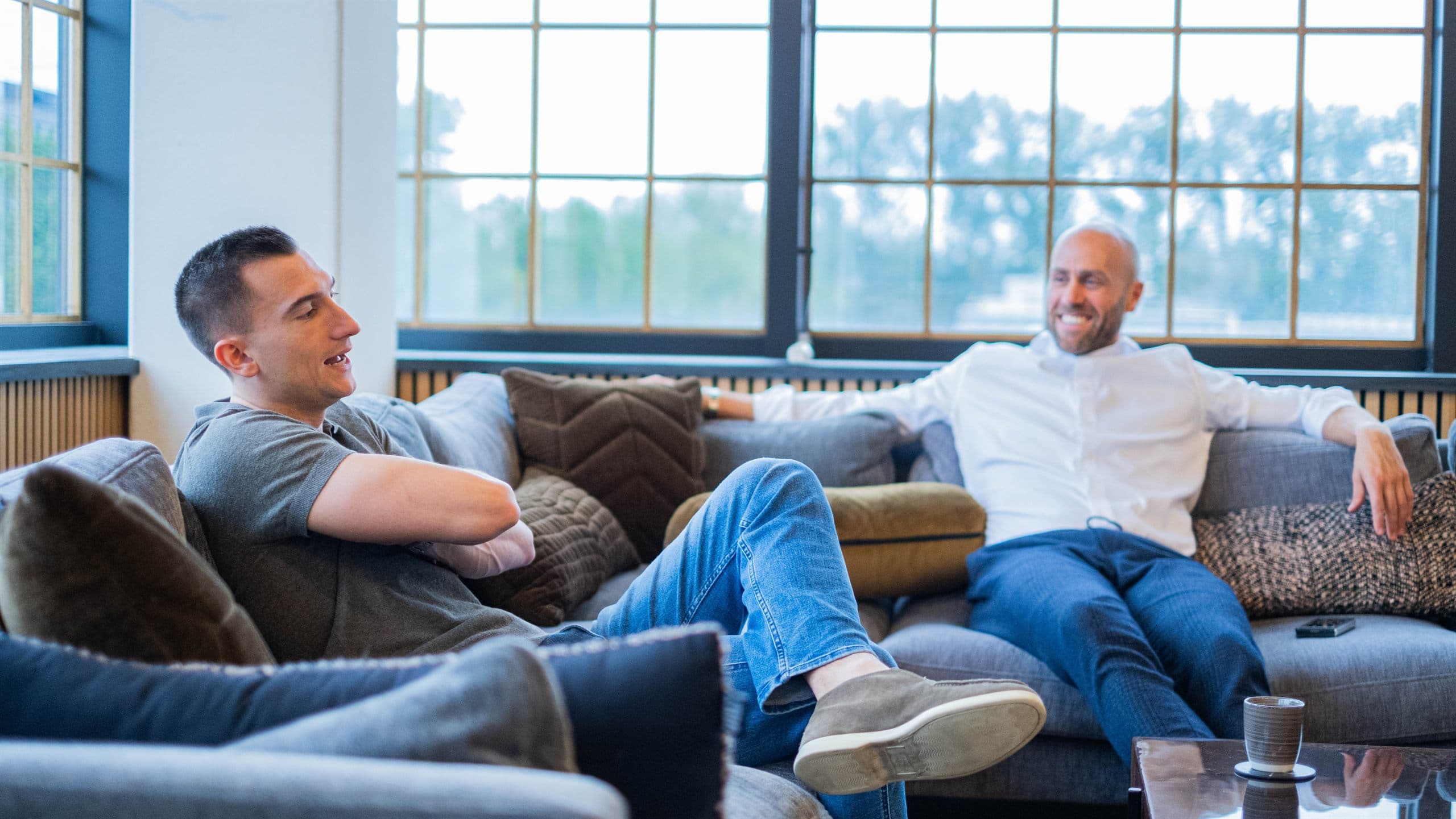 Two professionals in conversation at a table in an Amsterdam canal-side office